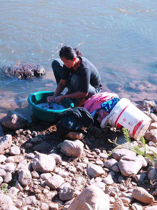 Woman doing laundry at river's edge