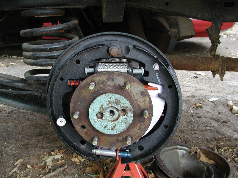 place strut and spring between shoes. Note position! It is installed in this pic exactly as it is shown in the parts pile above