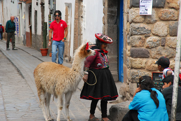 Girl in traditional clothes hunting for tourists with a llama