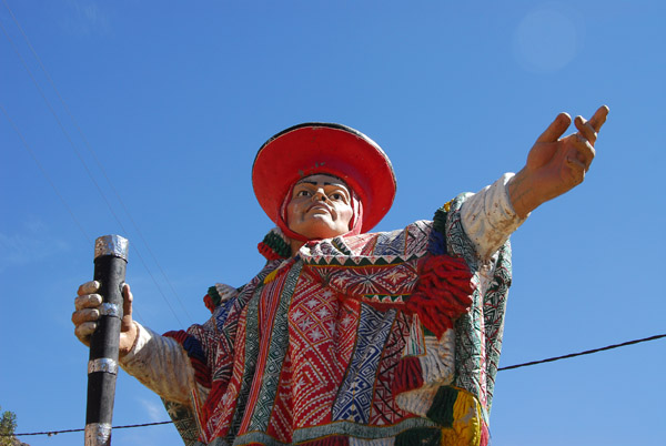 Statue of a man in traditional clothing at the entrance to the village of Pisaq