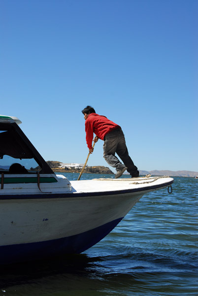 Crew member poling the boat alongside the pier