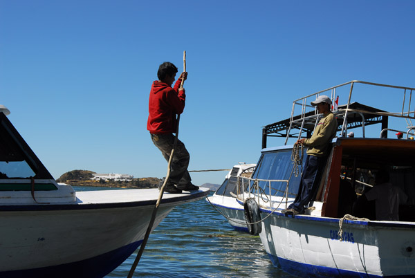 Crew member poling the boat alongside the pier