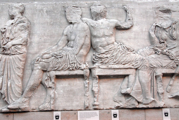 Hermes (figure 25) looks at the procession while leaning on the shoulder of Dionysos (figure 24), Parthon East Frieze IV