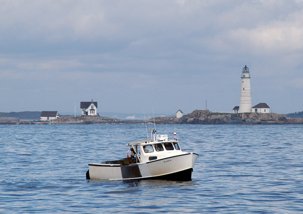 Small fishing boat in front of the Little Brewster Island lighthouse