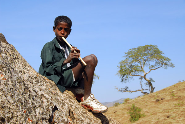 Ethiopia boy playing a washint, a traditional bamboo flute