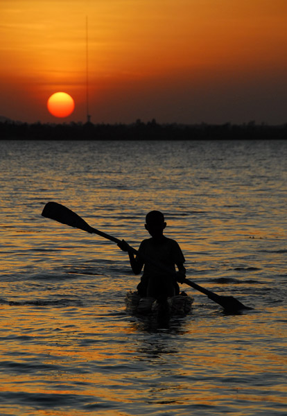 Boy paddling a reed boat at sunset, Lake Tana