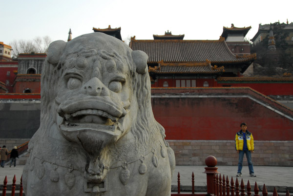 Lion at the base of the north side of Wanshou Shan with the Temple of the Four Buddhist States (Sida Buzhou) restored in 1980