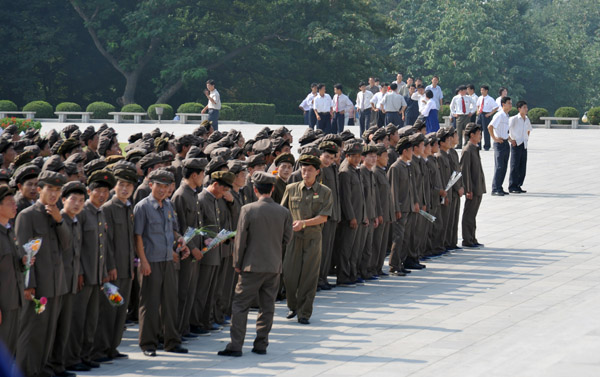 A large North Korean work unit dressed in Mao-suits arrives at the Mansu Grand Monument