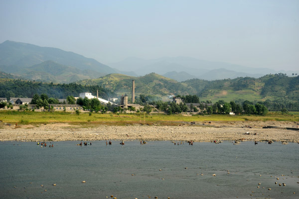 Factory town with North Koreans enjoying the Chongchon River on a hot day