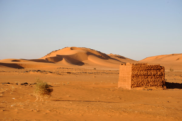 A small mudbrick hut with a large sand dune, Libyan Desert
