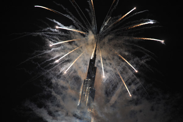 The pinnacle of Burj Khalifa stands out of the smoke as fireworks shoot out from the top