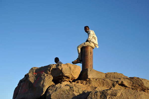 Sudanese man sitting on top of a pillar, Jebel Barkal