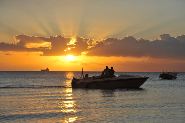 A boat cruises by at sunset, Mauritius