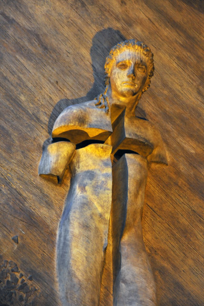 Figure of Christ in the style of an ancient sculpture emerging from the modern bronze door