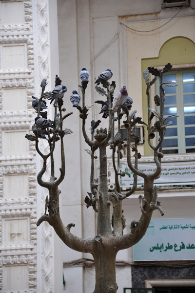 Sculpture of a tree and birds used by pigeons