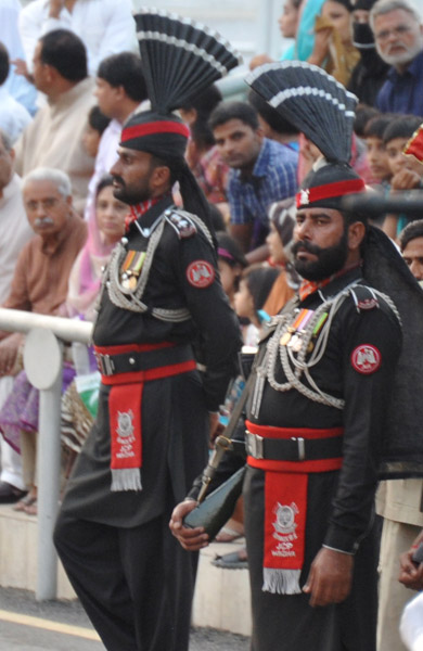 A Pakistani Ranger glances over as the crowd advances from the Indian side