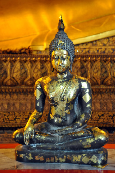 Small Buddha image with offerings of gold leaf