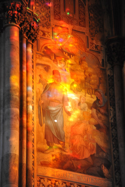 Stained glass casting colorful light on a wall mural