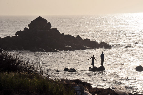 Boys playing on a rock just off shore, Cap-Verte