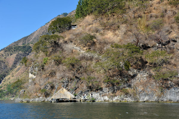Dock with a thatched shelter at the base of a path leading up the hillside
