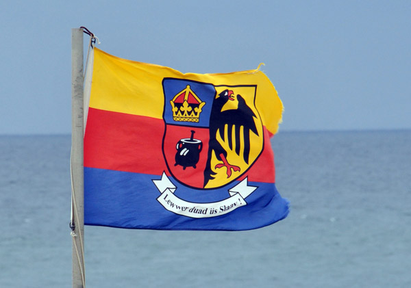 North Friesian flag with the motto Lewwer daud üs Slaav!