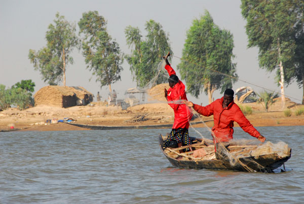 Fishermen using nets cast from a small pirogue
