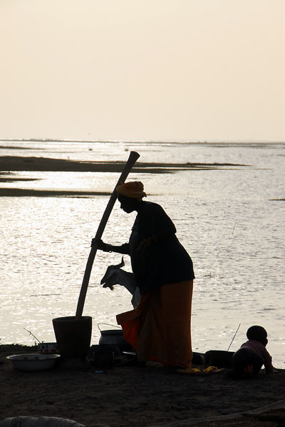Silhouette of a woman grinding millet