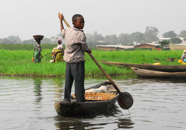 Young boy paddling a canoe, Ganvi