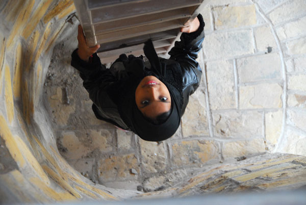 A girl climbing the ladder as Ras Sawadi tower