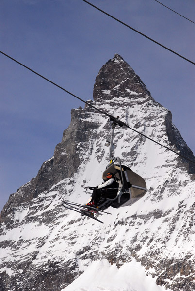 Skiers on a chairlift with the Matterhorn