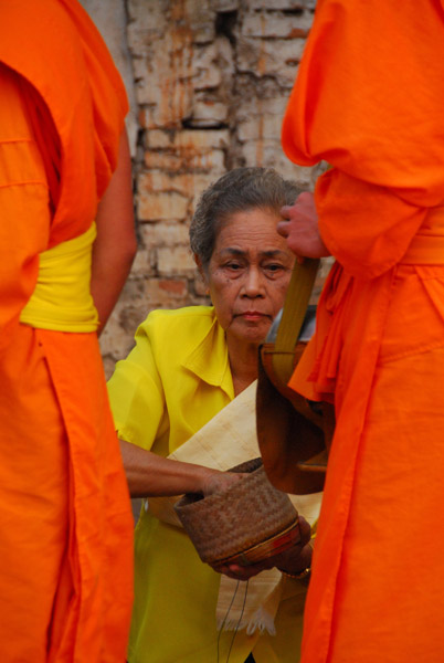 Woman giving alms to the monks