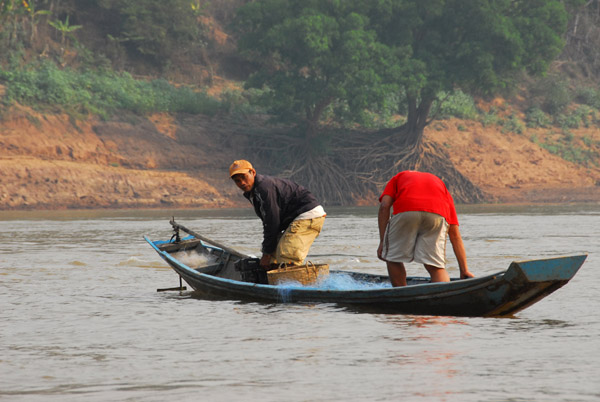 Two men with nets for fishing in a small boat