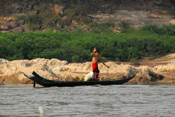 Boy waving from a small boat on the Mekong