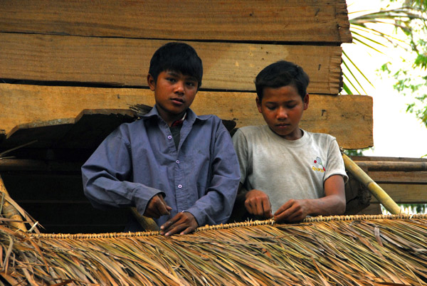 Lao boys making a roof with palm branches
