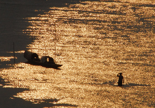 Person wading in the Mekong at sunset