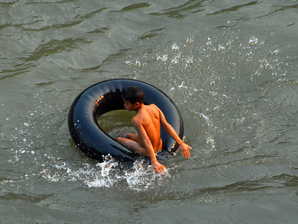 Lao boy floating down the Nam Khan River in an inner tube