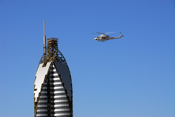 Dubai Police helicopter with the top of the Rose Rotana Tower Hotel