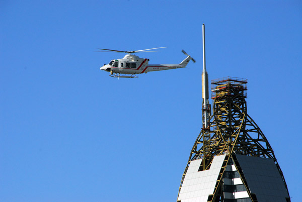 Dubai Police helicopter with the top of the Rose Rotana Tower Hotel