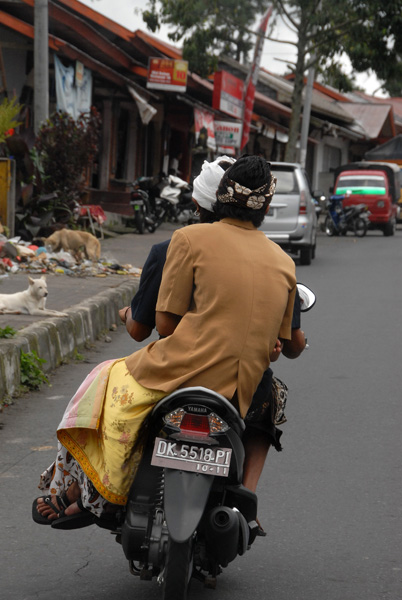 Balinese man in a sarong riding sidesaddle