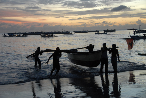 Fisherman bringing an outrigger canoe to shore, Jimbaren, Bali