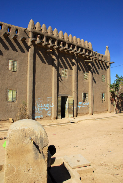 Water pump in front of a house hit by grafitti