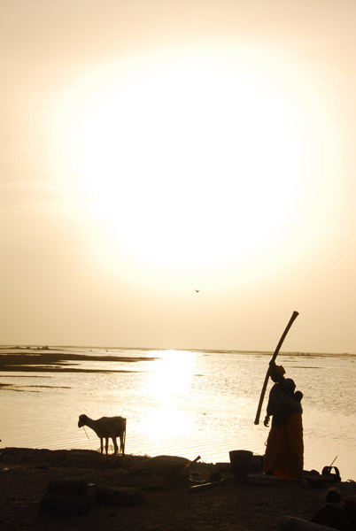 Woman grinding millet with the late afternoon sun