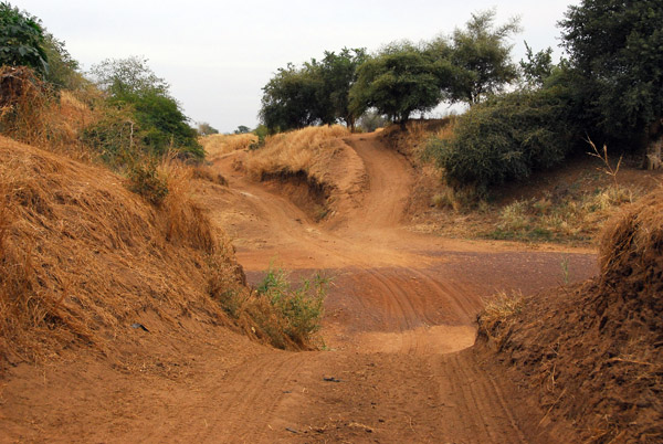 The track descends to cross a dry river bed south of Sélinkégni, Mali