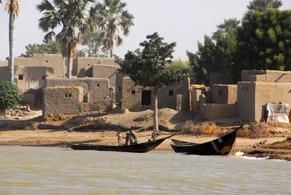 Mudbrick village with palm trees and fishing boats, Niger River, Mali