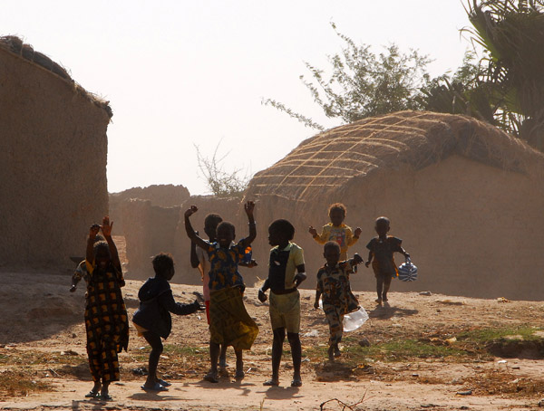 Excited kids waving from the river bank, Mali