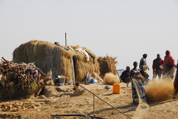Fisher people preparing their nets by a grass hut, Niger River, Mali