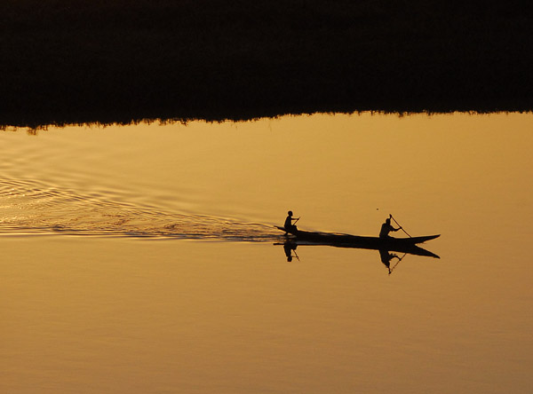 Two men in a pirogue crossing the Niger at sunset, Niamey