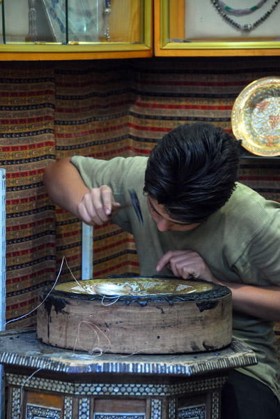 Craftsman beating silver and copper thread into a brass plate, Badreddin Al-Hassan Street