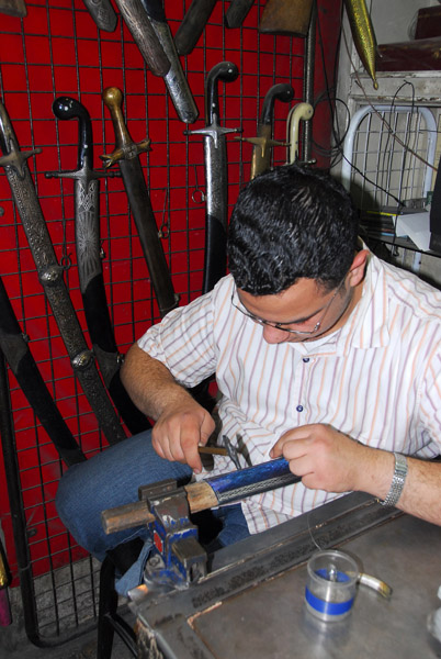 Swordsmith apprentice at work on a scabbard