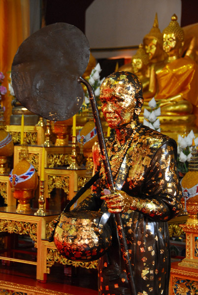 Monk statue with offerings of gold leaf
